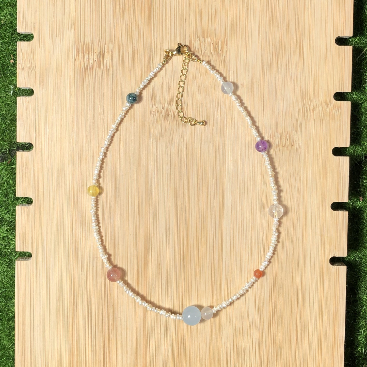 Eine handgefertigte Halskette mit natürlichen Süßwasserperlen und farbigen Edelsteinen, die die acht Planeten darstellen.