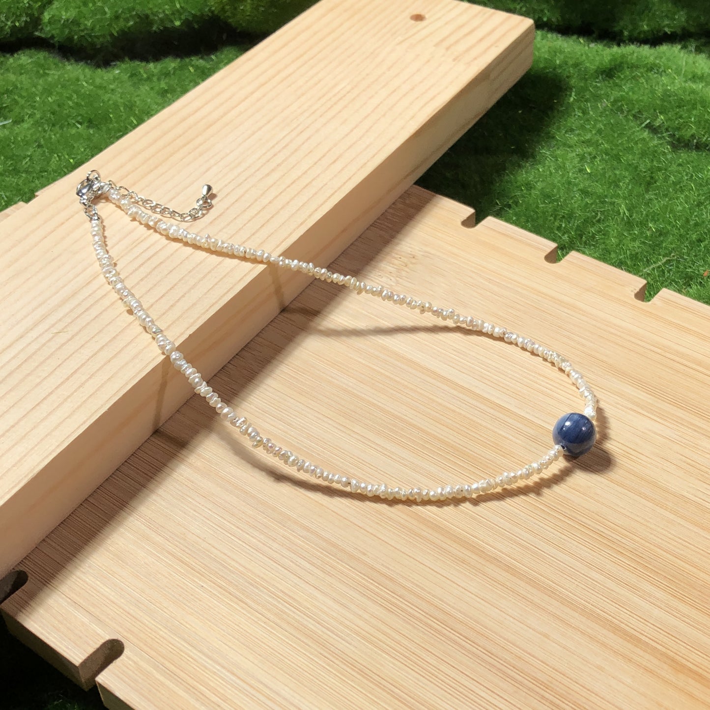 Eine handgefertigte Halskette aus natürlichen Süßwasserperlen und blauen Kristallen, aus mit 14-karätigem Gold plattiertem Kupfer.