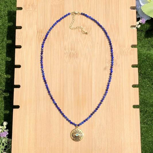 Halskette mit Anhänger in Form des Bösen Blicks aus Lapislazuli, Kette aus Titanstahl, 14 Karat vergoldet.
