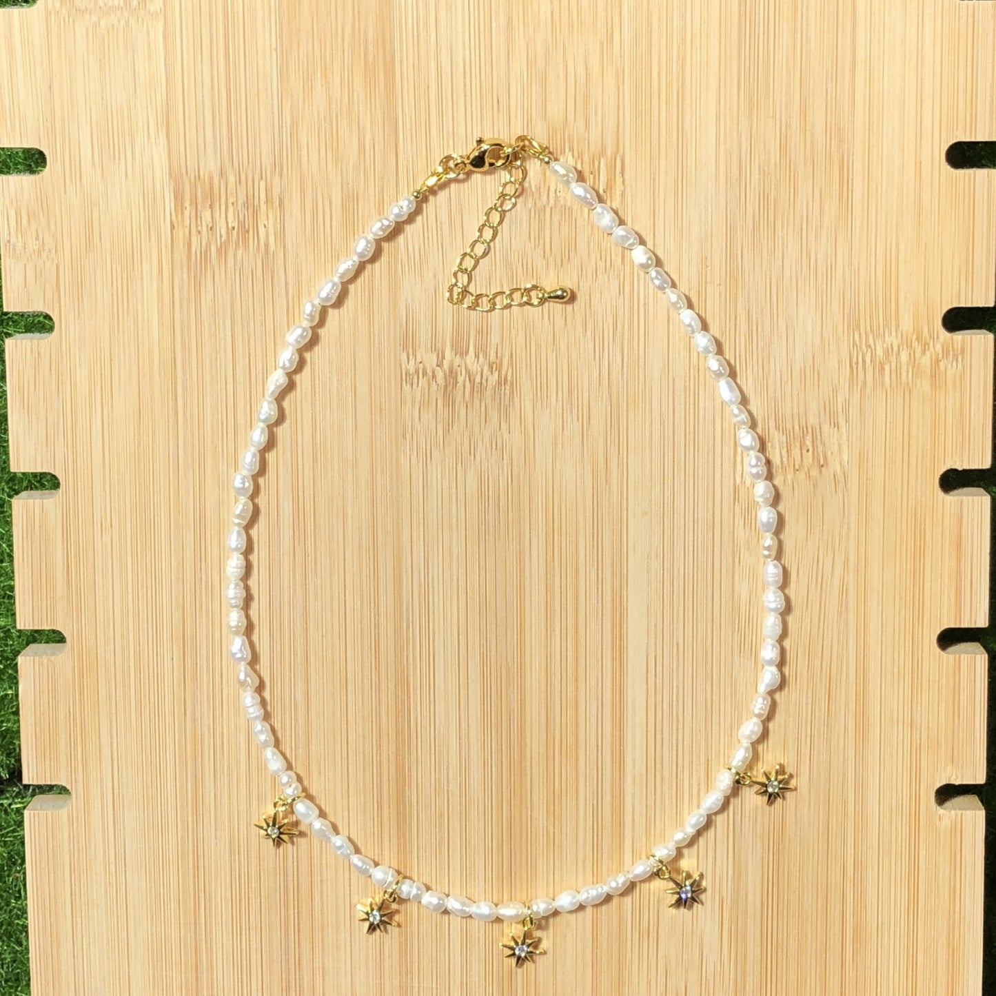 Eine handgefertigte Halskette aus natürlichen Süßwasserperlen mit einem 14-karätig vergoldeten Kupfer-Sonnenanhänger.