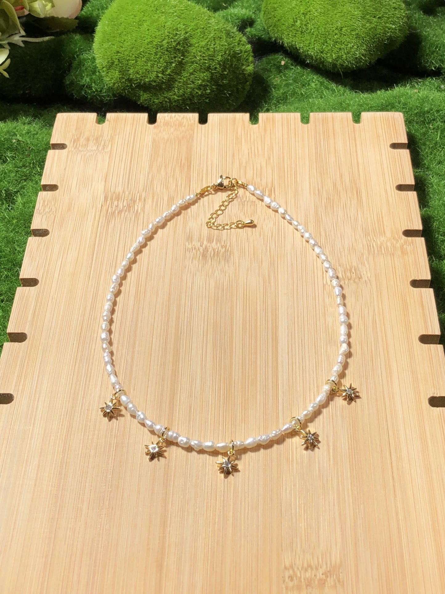 Eine handgefertigte Halskette aus natürlichen Süßwasserperlen mit einem 14-karätig vergoldeten Kupfer-Sonnenanhänger.