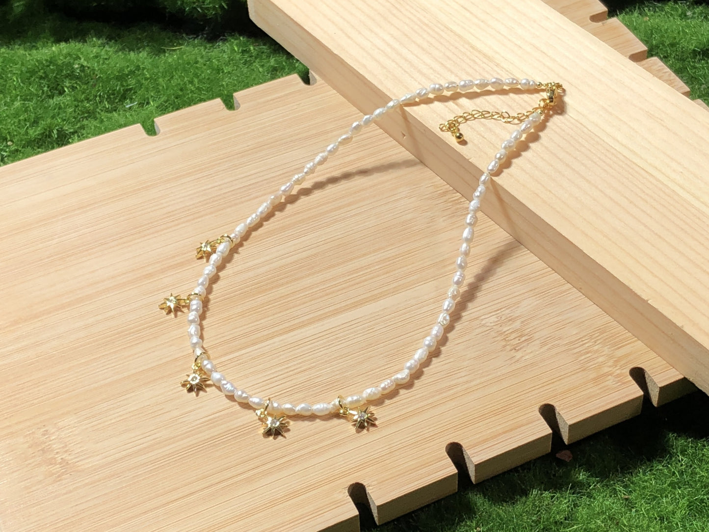 Eine handgefertigte Halskette aus natürlichen Süßwasserperlen mit einem 14-karätig vergoldeten Kupfer-Sonnenanhänger.