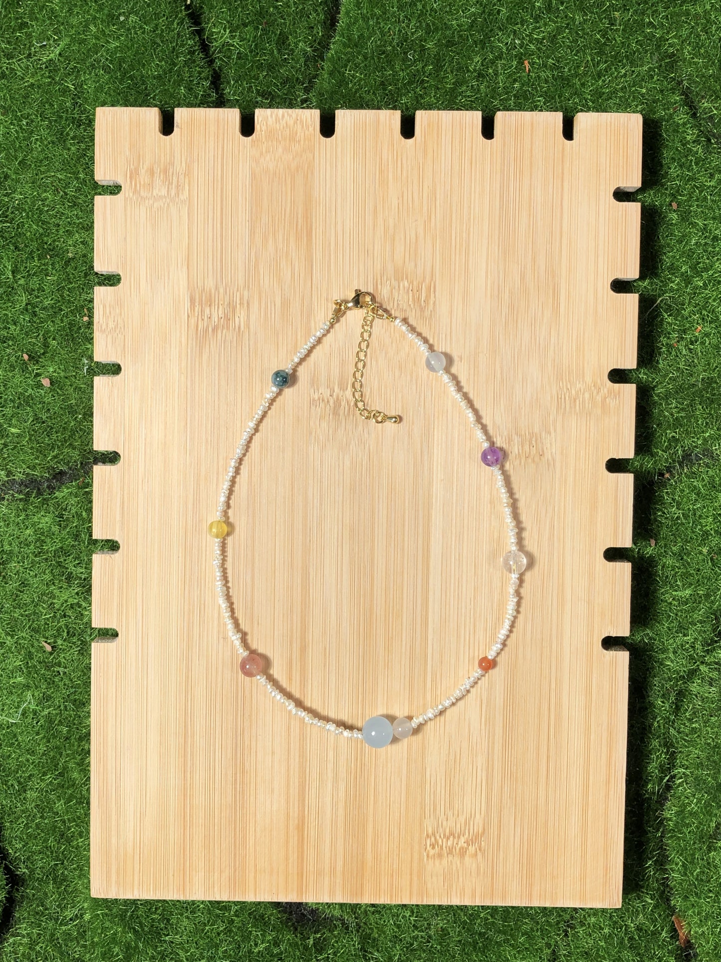 Eine handgefertigte Halskette mit natürlichen Süßwasserperlen und farbigen Edelsteinen, die die acht Planeten darstellen.