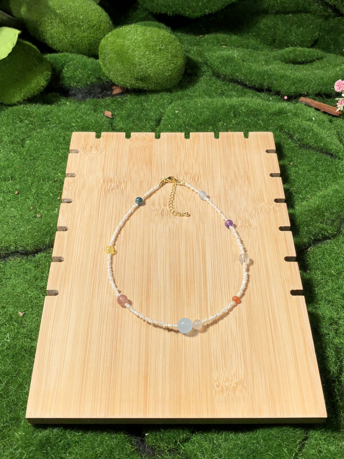 Eine handgefertigte Halskette mit natürlichen Süßwasserperlen und farbigen Edelsteinen, die die acht Planeten darstellen.