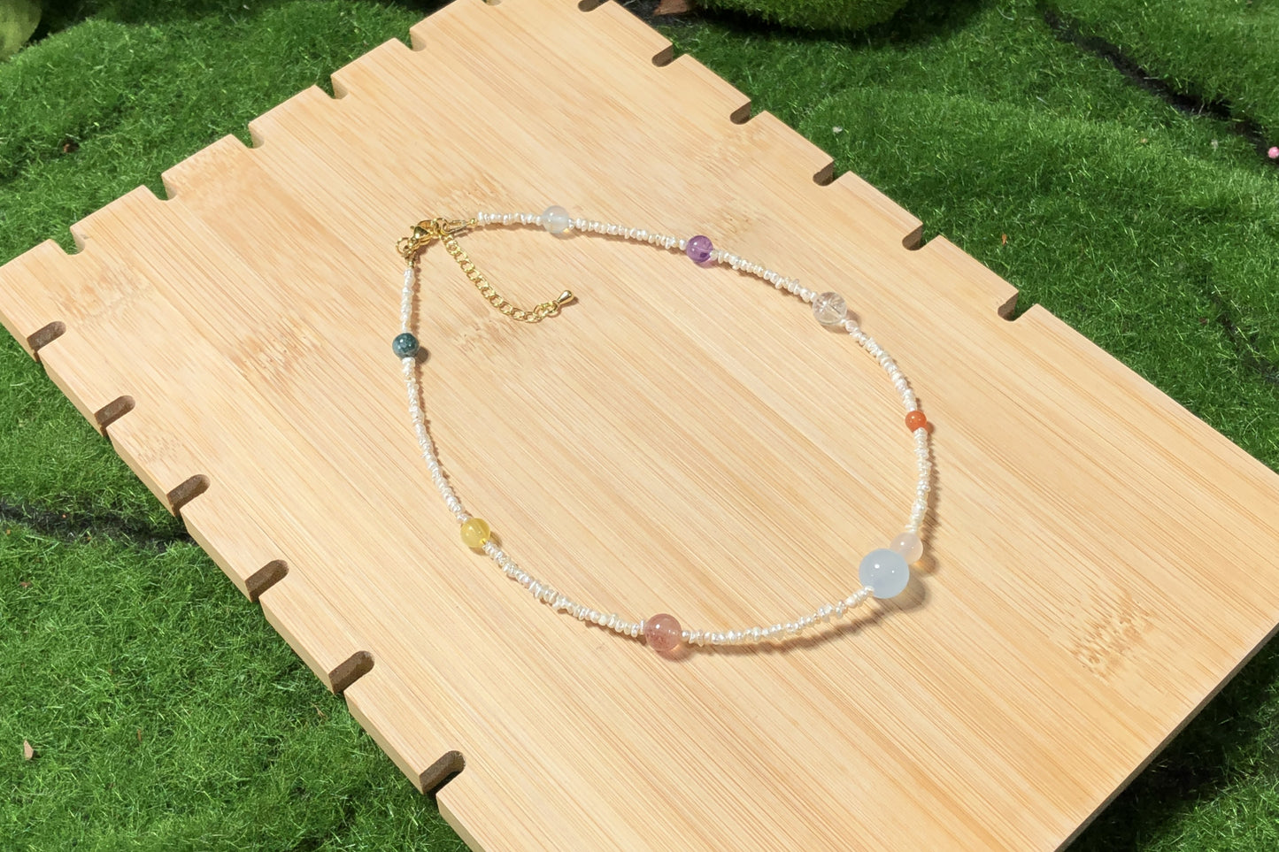 Eine handgefertigte Halskette mit natürlichen Süßwasserperlen und farbigen Edelsteinen, die die acht Planeten darstellen.