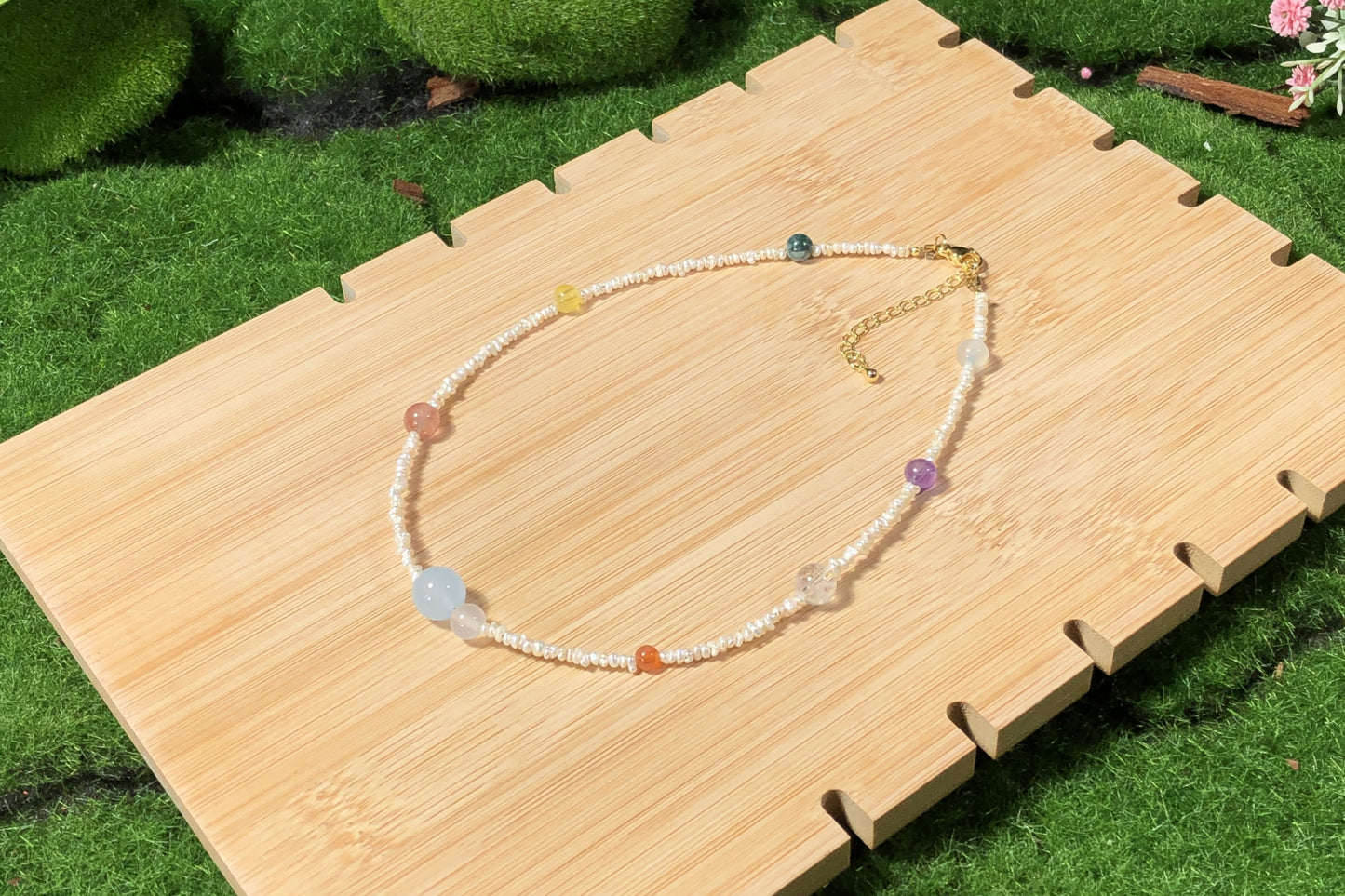Eine handgefertigte Halskette mit natürlichen Süßwasserperlen und farbigen Edelsteinen, die die acht Planeten darstellen.