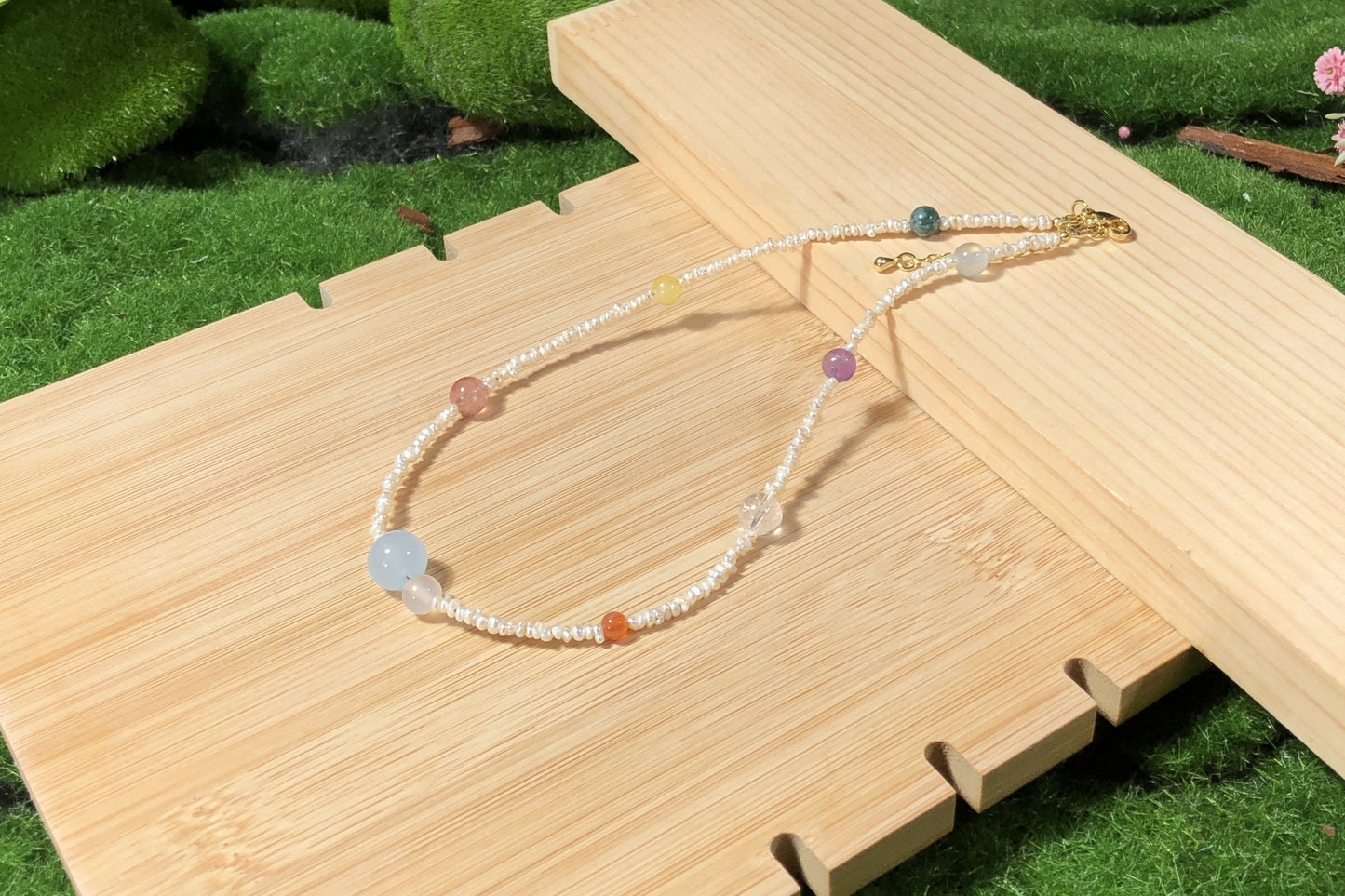 Eine handgefertigte Halskette mit natürlichen Süßwasserperlen und farbigen Edelsteinen, die die acht Planeten darstellen.