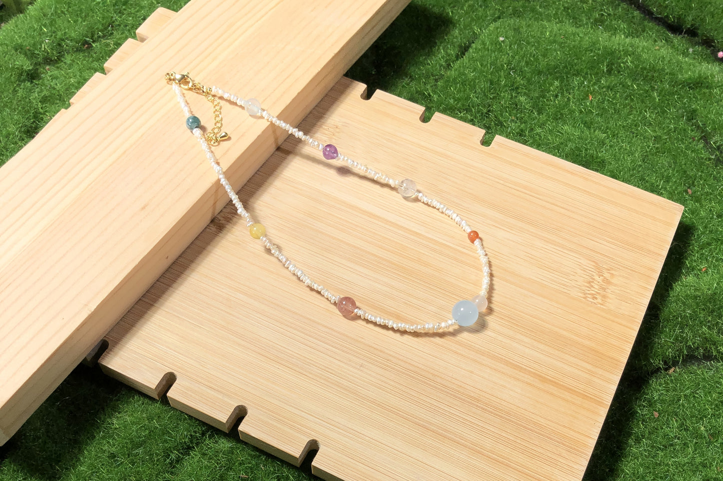 Eine handgefertigte Halskette mit natürlichen Süßwasserperlen und farbigen Edelsteinen, die die acht Planeten darstellen.