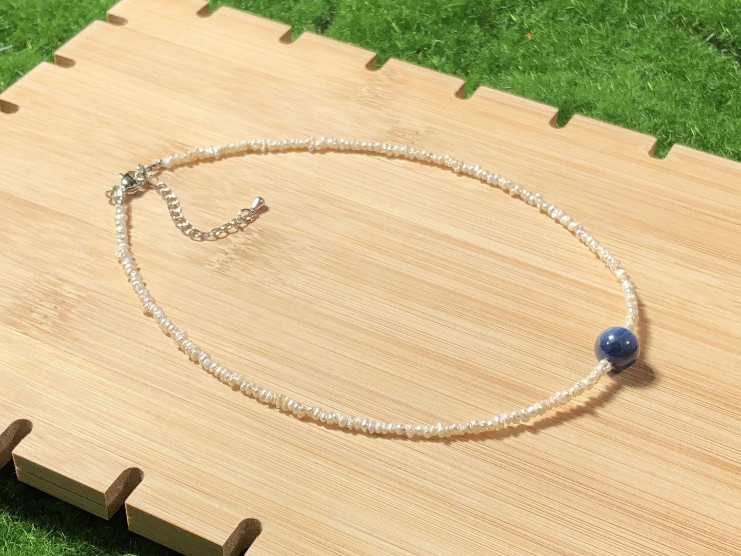 Eine handgefertigte Halskette aus natürlichen Süßwasserperlen und blauen Kristallen, aus mit 14-karätigem Gold plattiertem Kupfer.