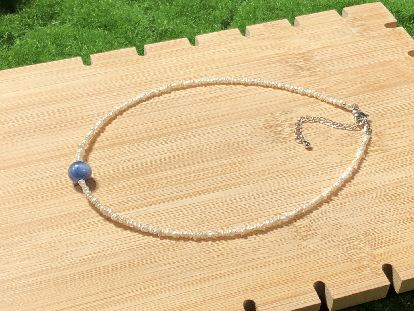 Eine handgefertigte Halskette aus natürlichen Süßwasserperlen und blauen Kristallen, aus mit 14-karätigem Gold plattiertem Kupfer.