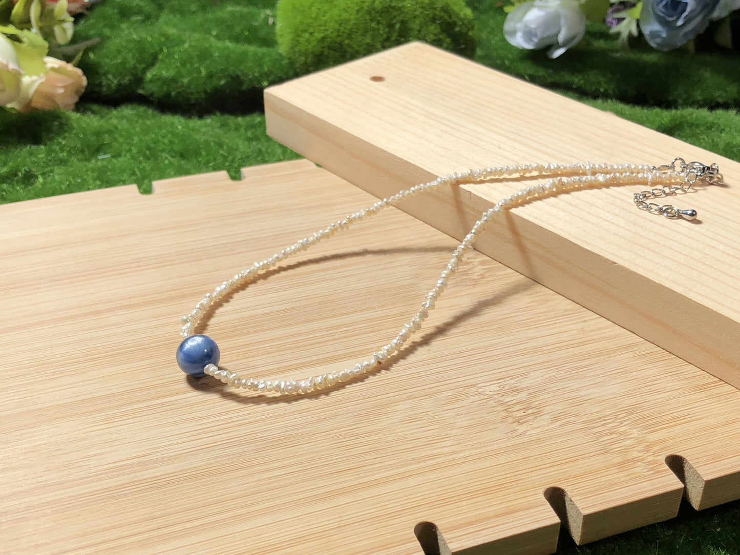 Eine handgefertigte Halskette aus natürlichen Süßwasserperlen und blauen Kristallen, aus mit 14-karätigem Gold plattiertem Kupfer.