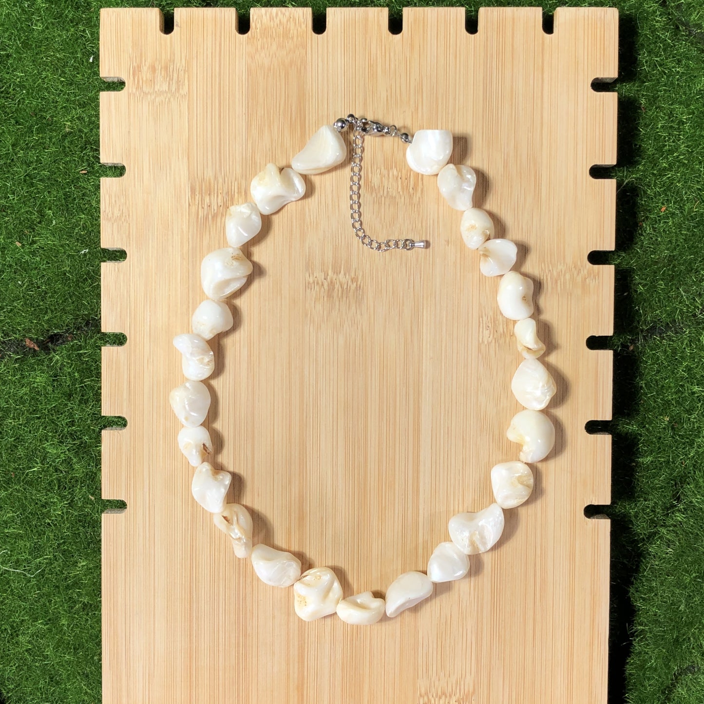 Eine unregelmäßige, handgefertigte Halskette aus weißen Muscheln mit einer Silberkette.
