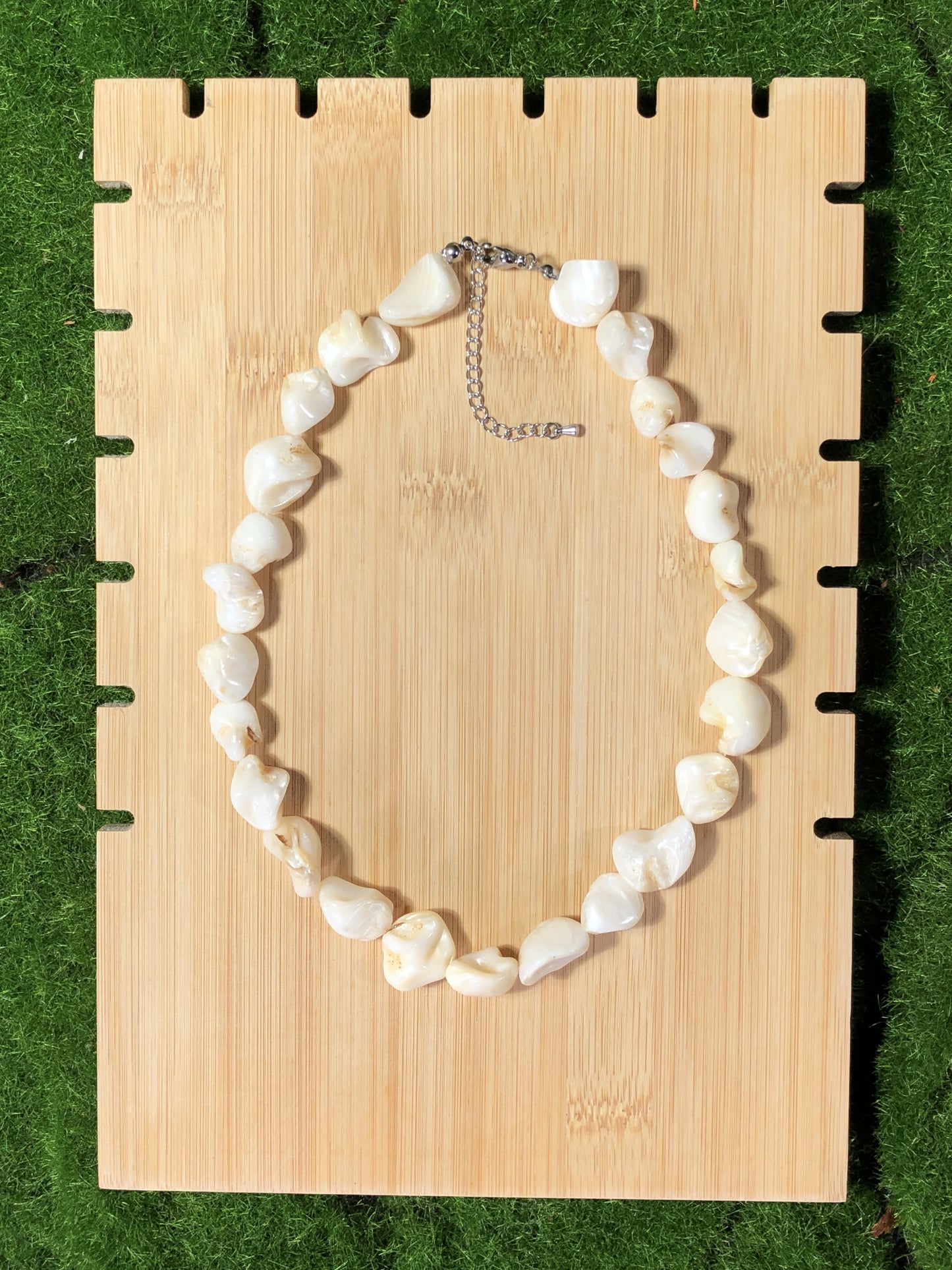 Eine unregelmäßige, handgefertigte Halskette aus weißen Muscheln mit einer Silberkette.