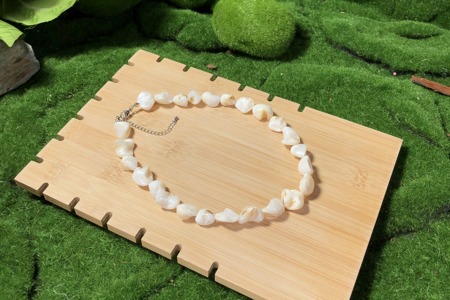 Eine unregelmäßige, handgefertigte Halskette aus weißen Muscheln mit einer Silberkette.