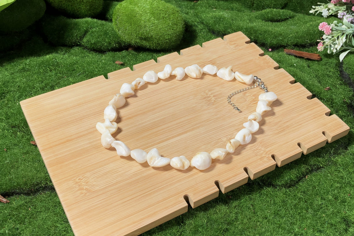 Eine unregelmäßige, handgefertigte Halskette aus weißen Muscheln mit einer Silberkette.