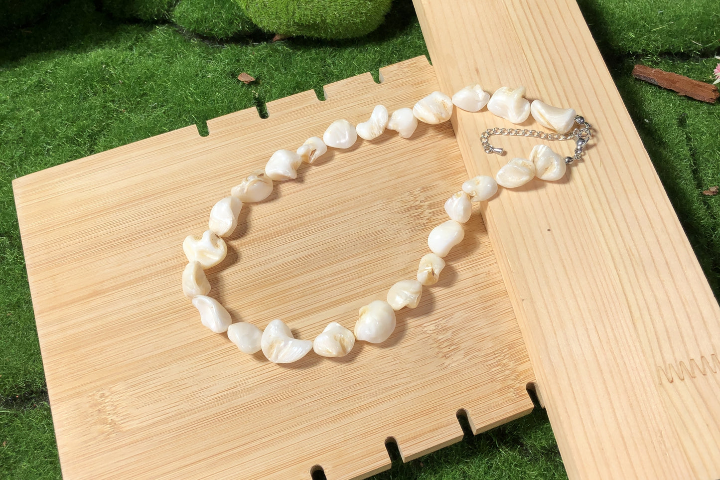 Eine unregelmäßige, handgefertigte Halskette aus weißen Muscheln mit einer Silberkette.