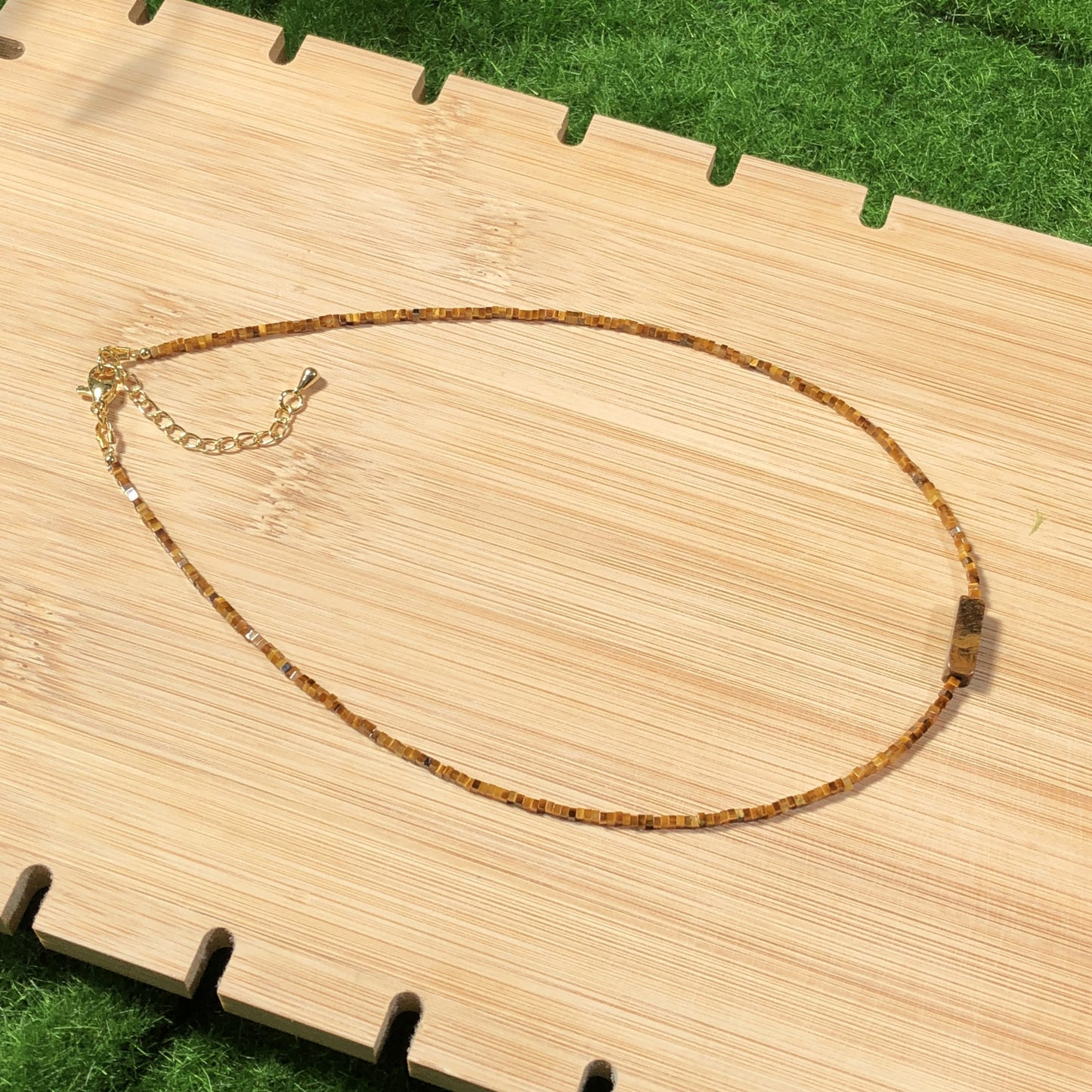 Dieses handgefertigte Schmuckstück besteht aus quadratischen Perlen aus natürlichem Tigerauge und einem rechteckigen Anhänger aus quadratischen Perlen.