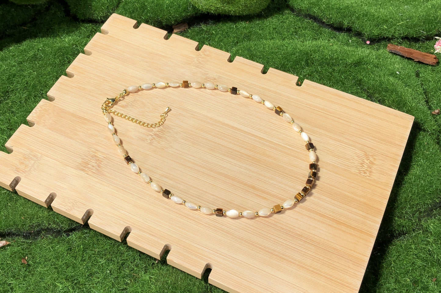 Eine handgefertigte Halskette mit Muschel- und natürlichen Tigeraugen-Würfelperlen und einer 14-karätig verkupferten Goldkette.