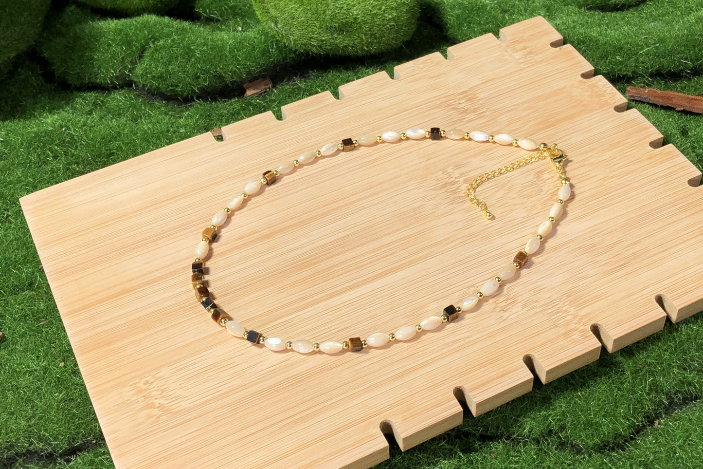 Eine handgefertigte Halskette mit Muschel- und natürlichen Tigeraugen-Würfelperlen und einer 14-karätig verkupferten Goldkette.